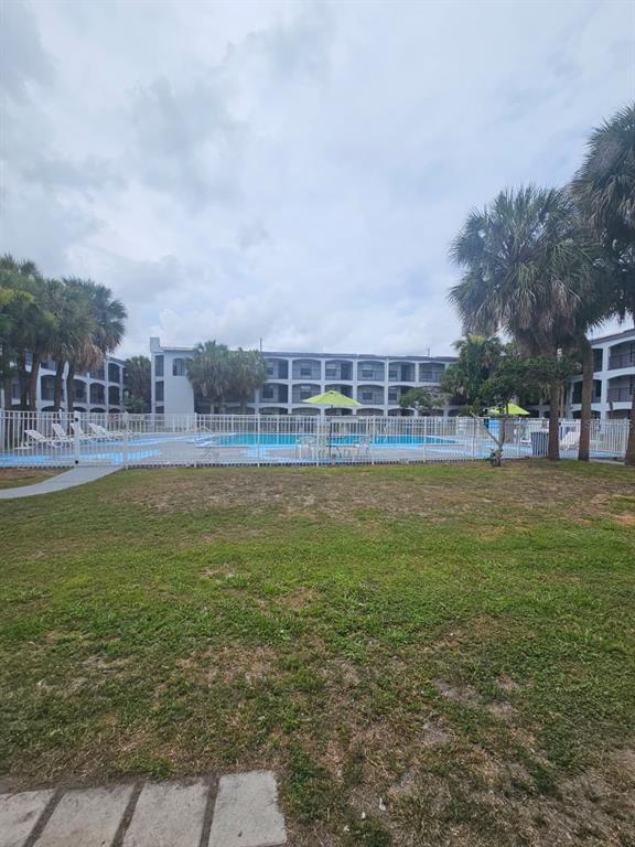A swimming pool with lounge chairs and umbrellas sits in front of a multi-story building — 2323 MCCOY ROAD UNIT 801, ORLANDO, FL
