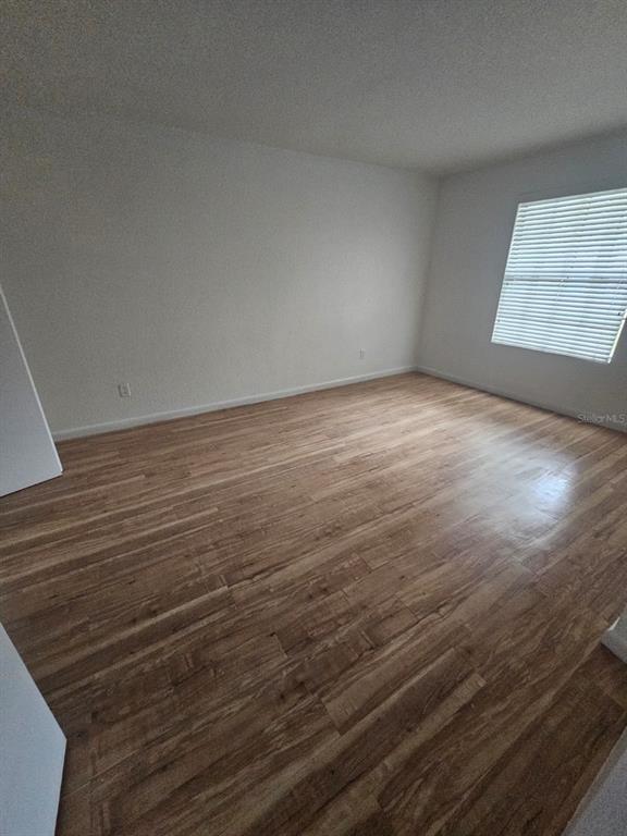 An empty room features light-colored walls, wood-look flooring, and a window with white blinds — 2323 MCCOY ROAD UNIT 801, ORLANDO, FL