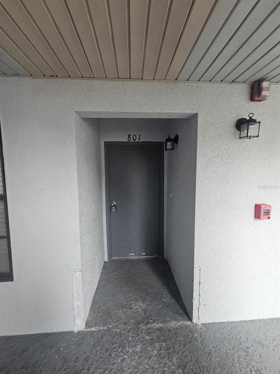 A gray exterior door marked 801 is recessed into a light-colored stucco wall — 2323 MCCOY ROAD UNIT 801, ORLANDO, FL