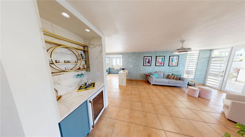 A wet bar with gold shelving overlooks a living room with tile floors and furniture — D7 ZAFIRO, DORADO, PR