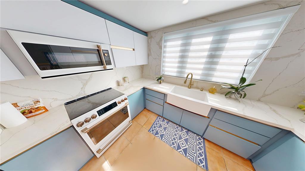 A kitchen features white upper cabinets, blue lower cabinets, a farmhouse sink, and marble countertops — D7 ZAFIRO, DORADO, PR