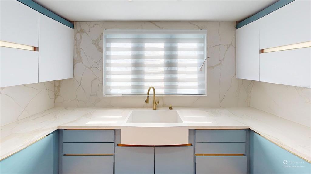 A kitchen features a white farmhouse sink, blue cabinets, and marble countertops and backsplash — D7 ZAFIRO, DORADO, PR