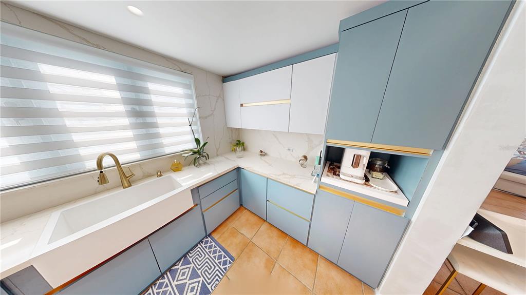 A kitchen features blue and white cabinets, gold hardware, and white marble-look countertops — D7 ZAFIRO, DORADO, PR