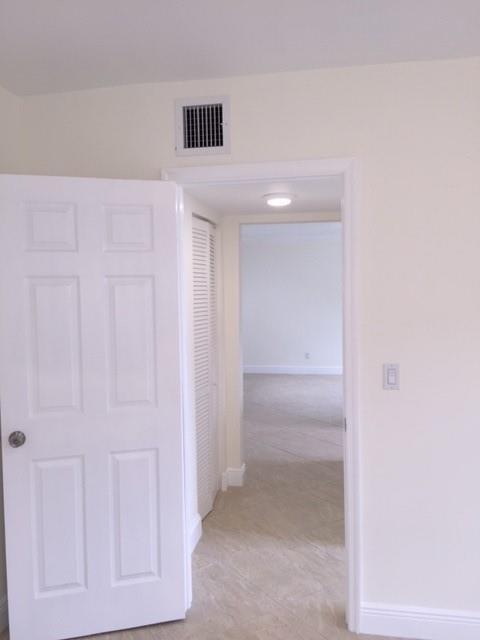 A white door opens into a hallway with tile flooring and a view of another room — NORTH MIAMI BEACH, FL