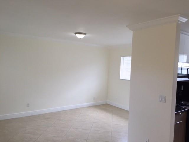 An empty room with light-colored walls, tile flooring, and a ceiling-mounted light fixture — NORTH MIAMI BEACH, FL