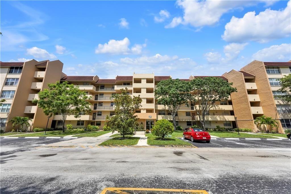 A multi-story tan apartment building with a parking lot and trees in front — 7080 Environ Boulevard # 522, Lauderhill FL 33319, LAUDERHILL, FL