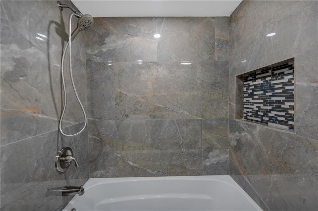 A bathtub with a handheld showerhead and a tiled niche in a gray-tiled shower surround — 7080 Environ Boulevard # 522, Lauderhill FL 33319, LAUDERHILL, FL