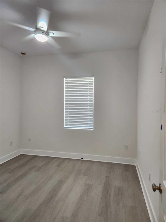 An empty bedroom with white walls, light wood-look flooring, a ceiling fan, and a window — 6514 GRAPEWOOD ROAD, SPRING HILL, FL