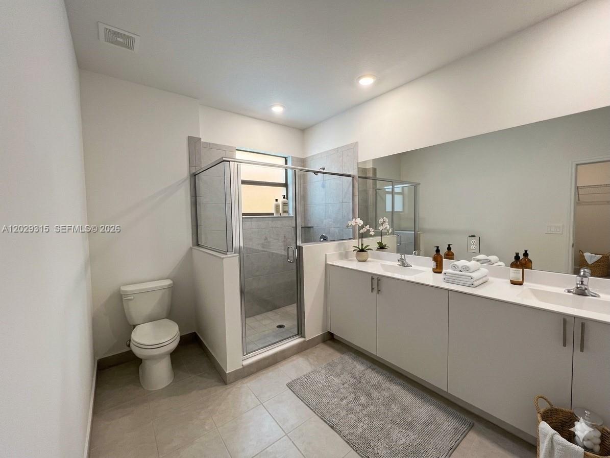 A modern bathroom features a double vanity, a glass-enclosed shower, and a toilet — 24600 SW 119th Pl # 0, Miami FL 33032, MIAMI, FL
