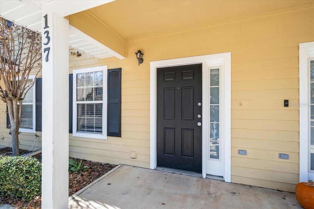 The front entrance features a black door, a sidelight, and a house number on a post — 2945 SW 35TH PLACE UNIT 137, GAINESVILLE, FL