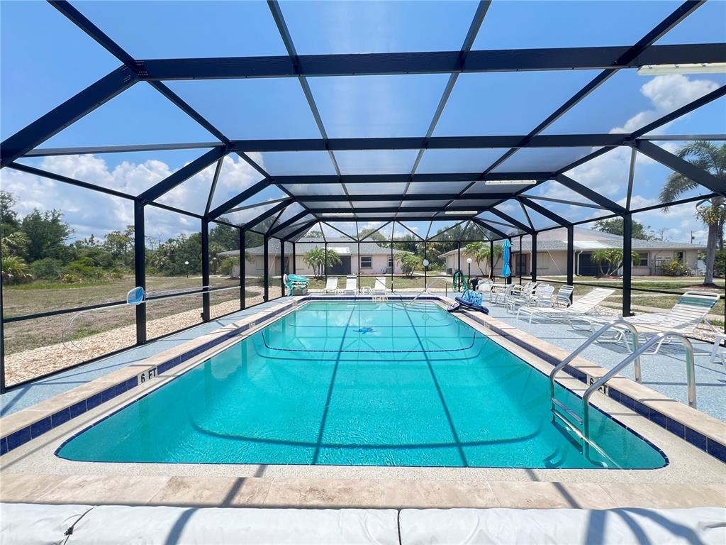 A rectangular swimming pool is enclosed by a screened lanai with lounge chairs on the deck — 25068 HARBORVIEW ROAD UNIT 1A, PUNTA GORDA, FL