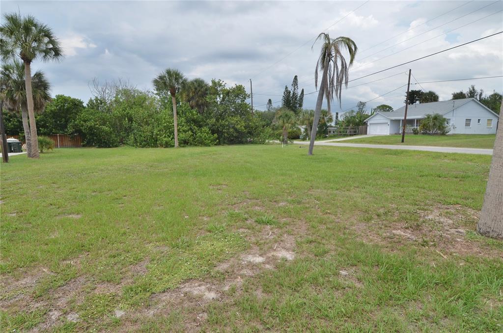 A grassy, vacant lot features several palm trees under a cloudy sky — 610 COQUINA COURT, NOKOMIS, FL