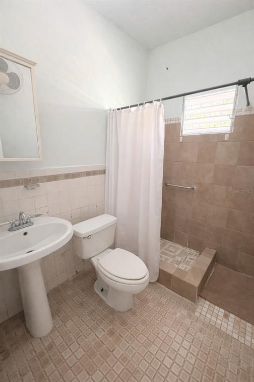 A bathroom features a pedestal sink, a toilet, and a tiled walk-in shower with curtains — PR 1 19.9, SAN JUAN, PR