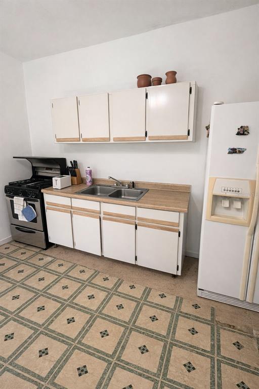 A kitchen features white cabinets, a double-basin sink, a gas stove, and patterned tile flooring — PR 1 19.9, SAN JUAN, PR