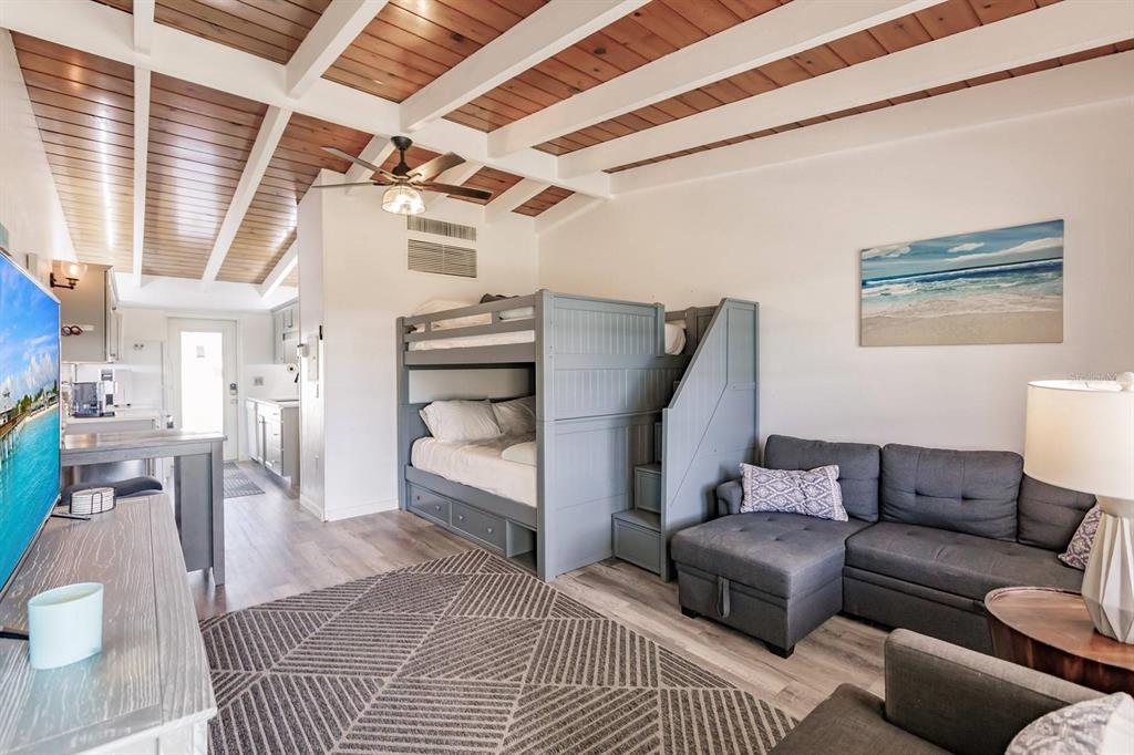 A living room features a gray bunk bed, a sectional sofa, and a wood-paneled ceiling — 6006 MIDNIGHT PASS ROAD UNIT 2, SARASOTA, FL
