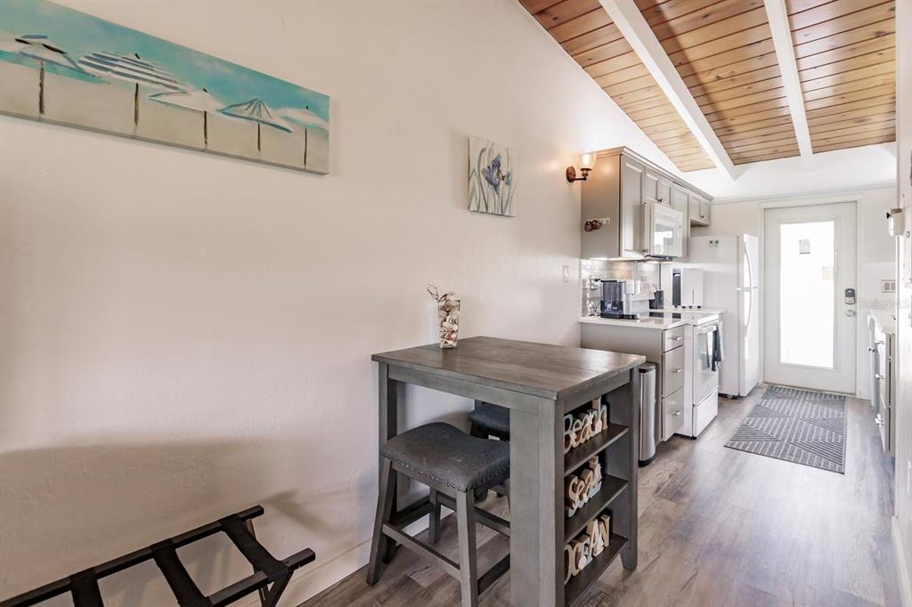 A kitchen and dining area features a wooden table, gray cabinets, and a wood-paneled ceiling — 6006 MIDNIGHT PASS ROAD UNIT 2, SARASOTA, FL