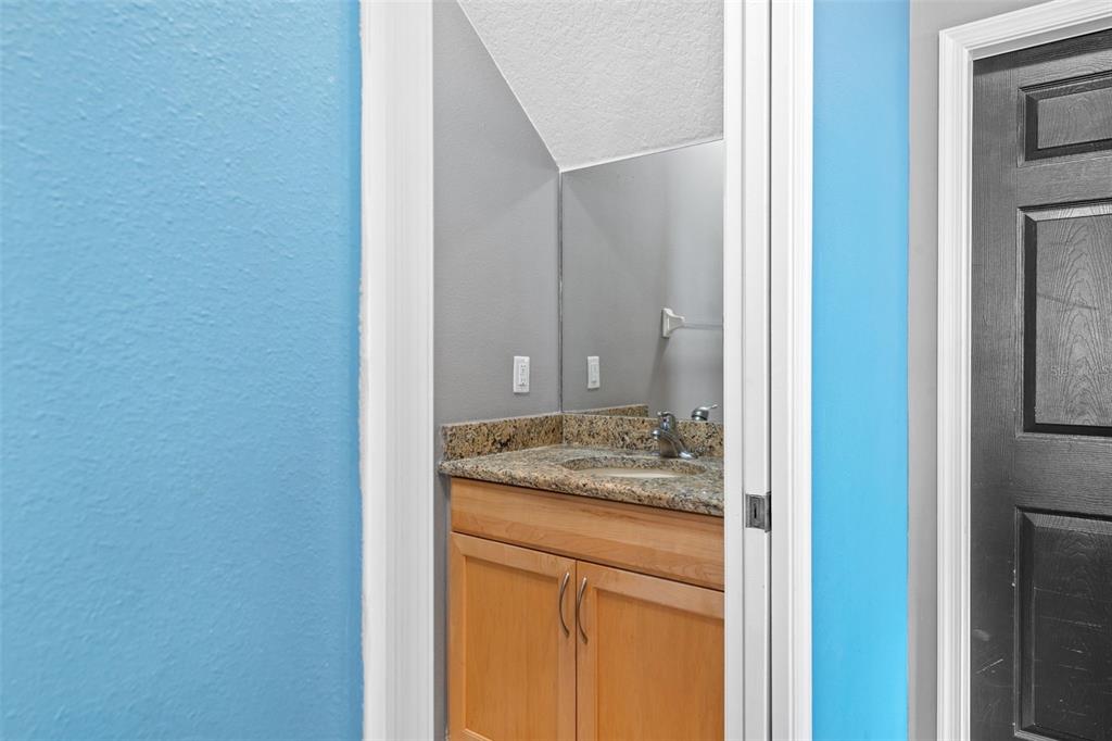 A bathroom vanity with a granite countertop and wooden cabinets sits in a small alcove — 19419 RED SKY COURT, LAND O LAKES, FL