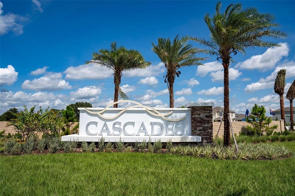 A white monument sign reading Cascades stands in front of palm trees and a blue sky — 2464 RIBBON FALL AVENUE, DAVENPORT, FL