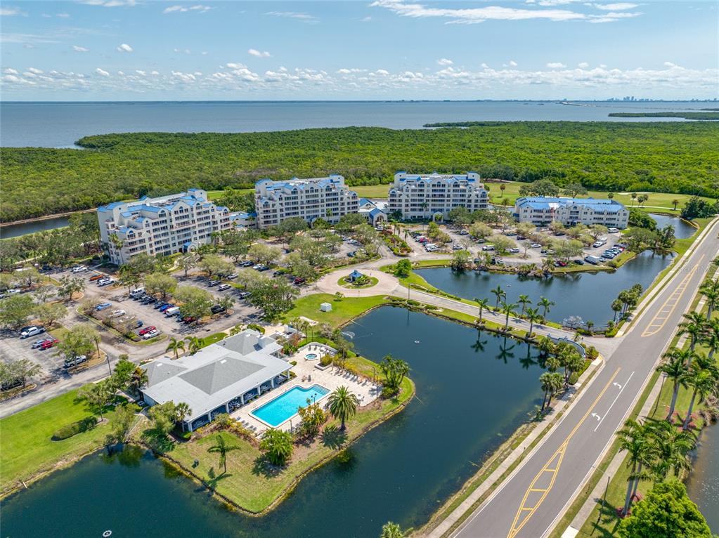 An aerial view shows a multi-building residential complex with a pool, ponds, and parking — 2333 FEATHER SOUND DRIVE UNIT A107, CLEARWATER, FL