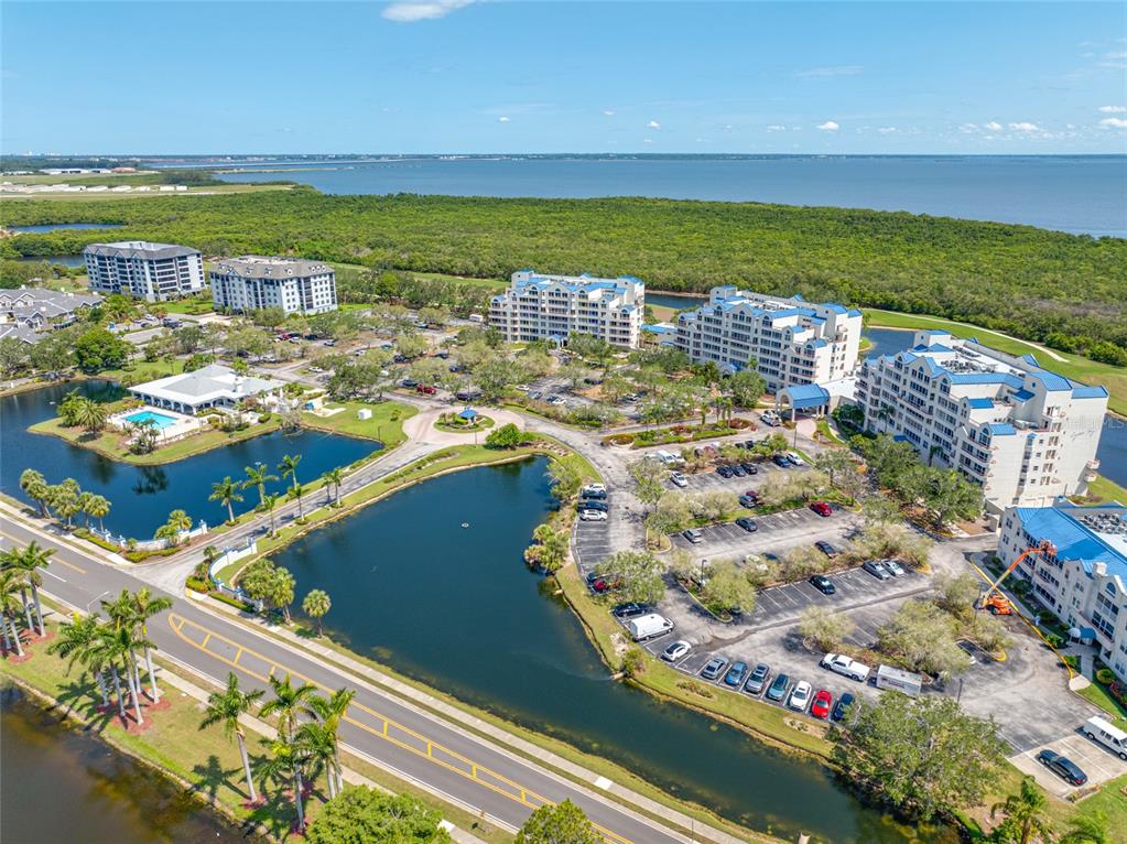 An aerial view shows a residential complex with multiple buildings, parking lots, and a pond — 2333 FEATHER SOUND DRIVE UNIT A107, CLEARWATER, FL