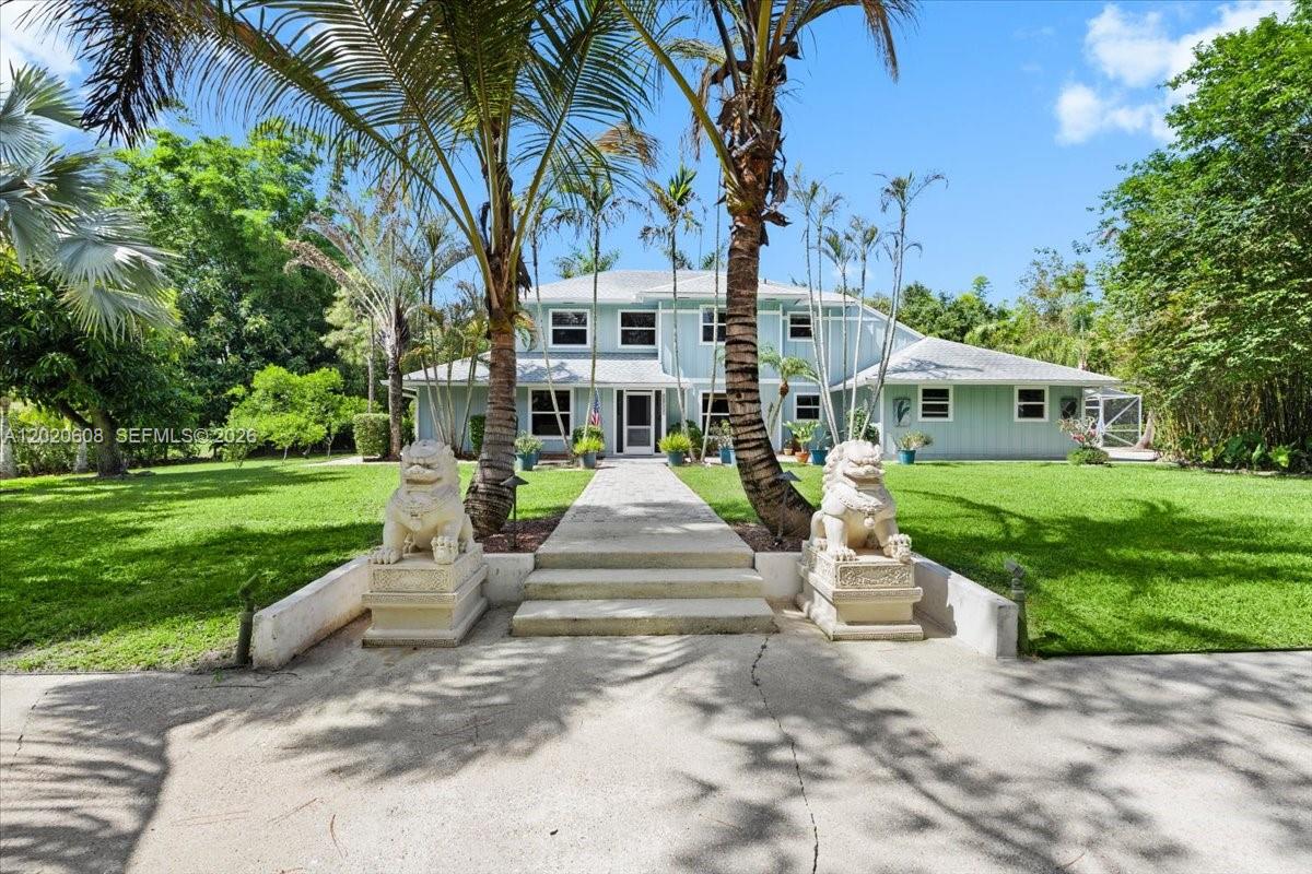 A two-story light blue house features a stone walkway flanked by two large lion statues — 10767 N 153rd Ct N, Jupiter FL 33478, JUPITER, FL