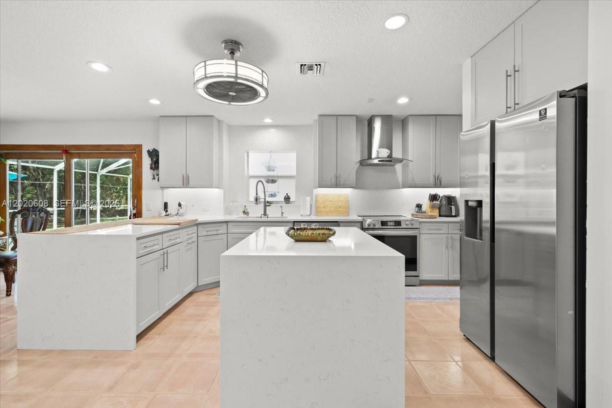 A modern kitchen features light gray cabinets, white quartz countertops, and a central island — 10767 N 153rd Ct N, Jupiter FL 33478, JUPITER, FL