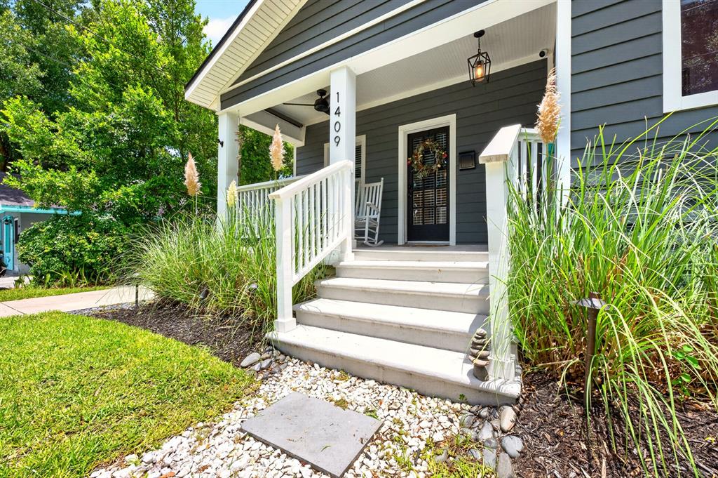 A gray house with a white front porch, stairs, and tall ornamental grasses — 1409 E GORE STREET, ORLANDO, FL