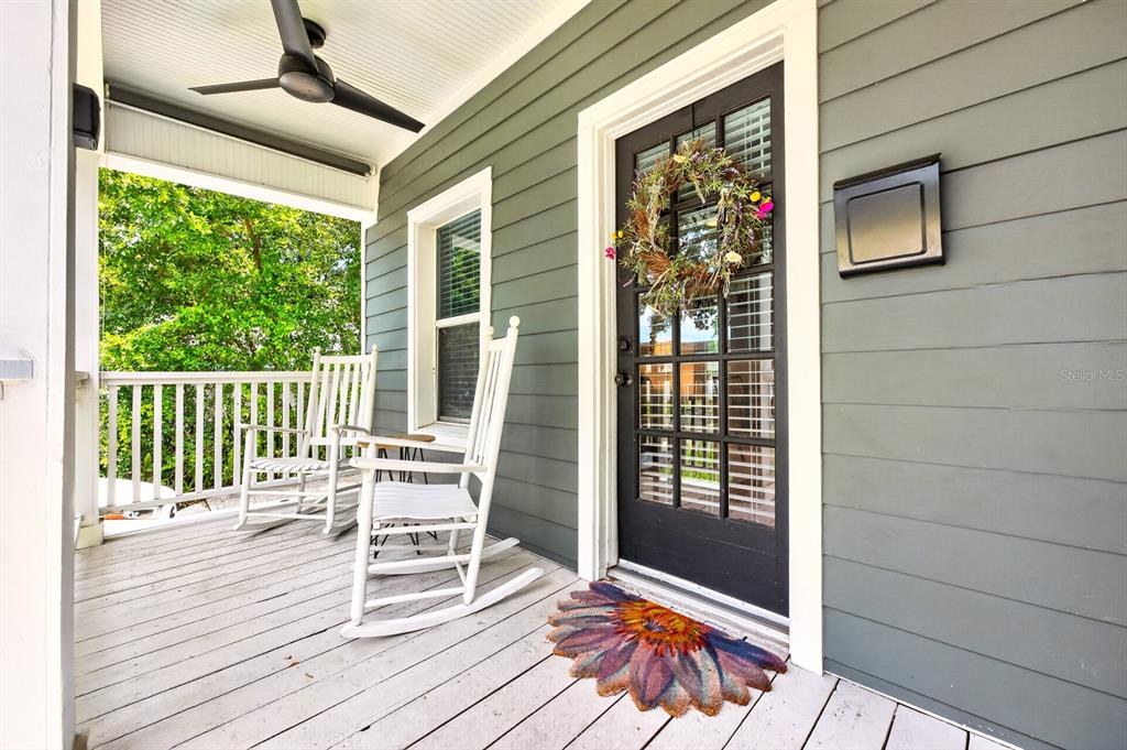 A covered front porch features two white rocking chairs, a black door, and gray siding — 1409 E GORE STREET, ORLANDO, FL