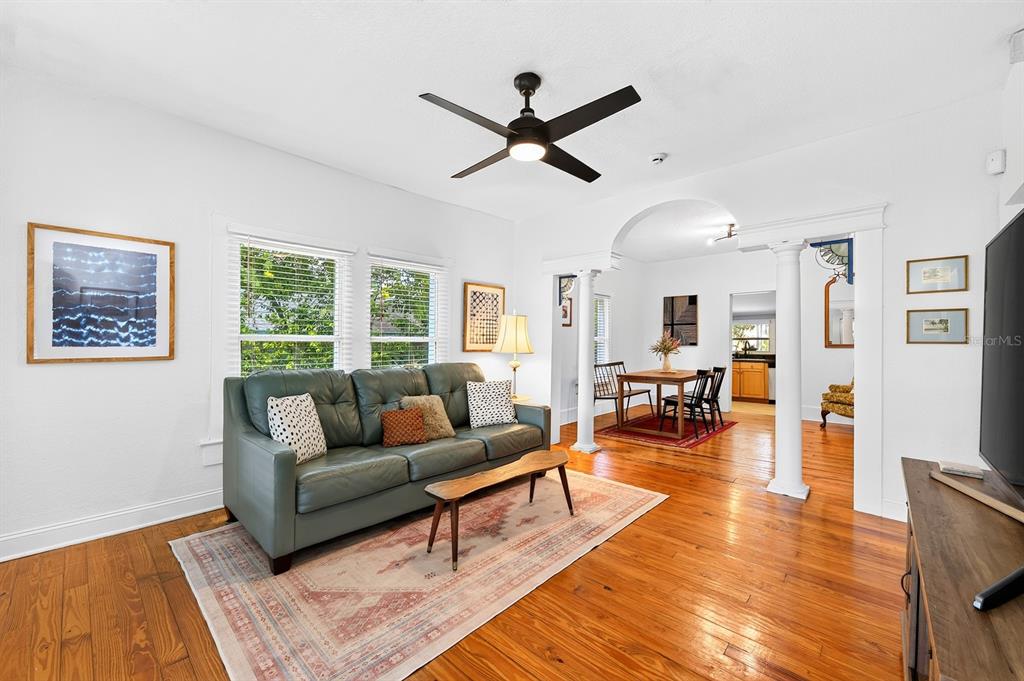 A living room with hardwood floors, a green sofa, and an arched opening to a dining area — 1409 E GORE STREET, ORLANDO, FL