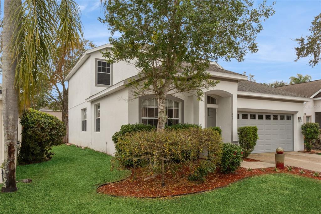 A two-story white house with a gray garage door and a front yard with landscaping — 367 HICKORY SPRINGS PLACE, DEBARY, FL