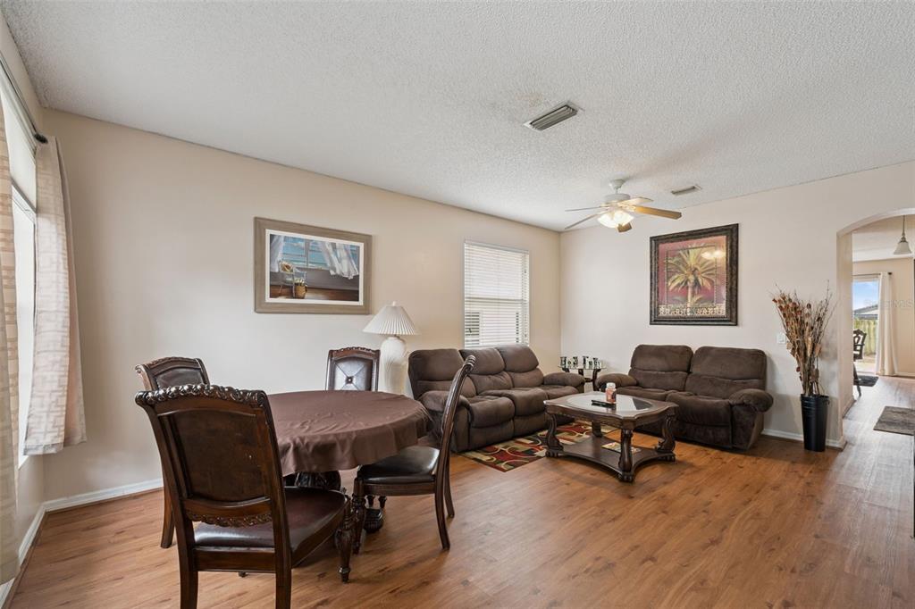 A living and dining area features wood-look flooring, brown furniture, and a ceiling fan — 367 HICKORY SPRINGS PLACE, DEBARY, FL