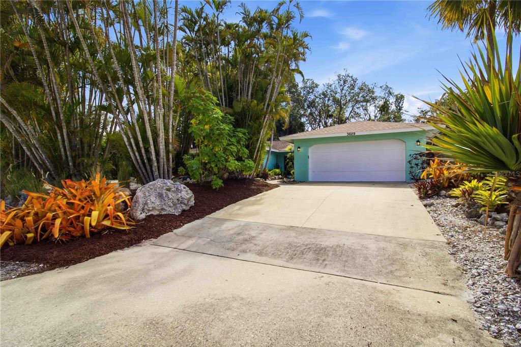 A light blue house with a two-car garage and tropical landscaping sits behind a driveway — 3629 EGERTON CIRCLE, SARASOTA, FL