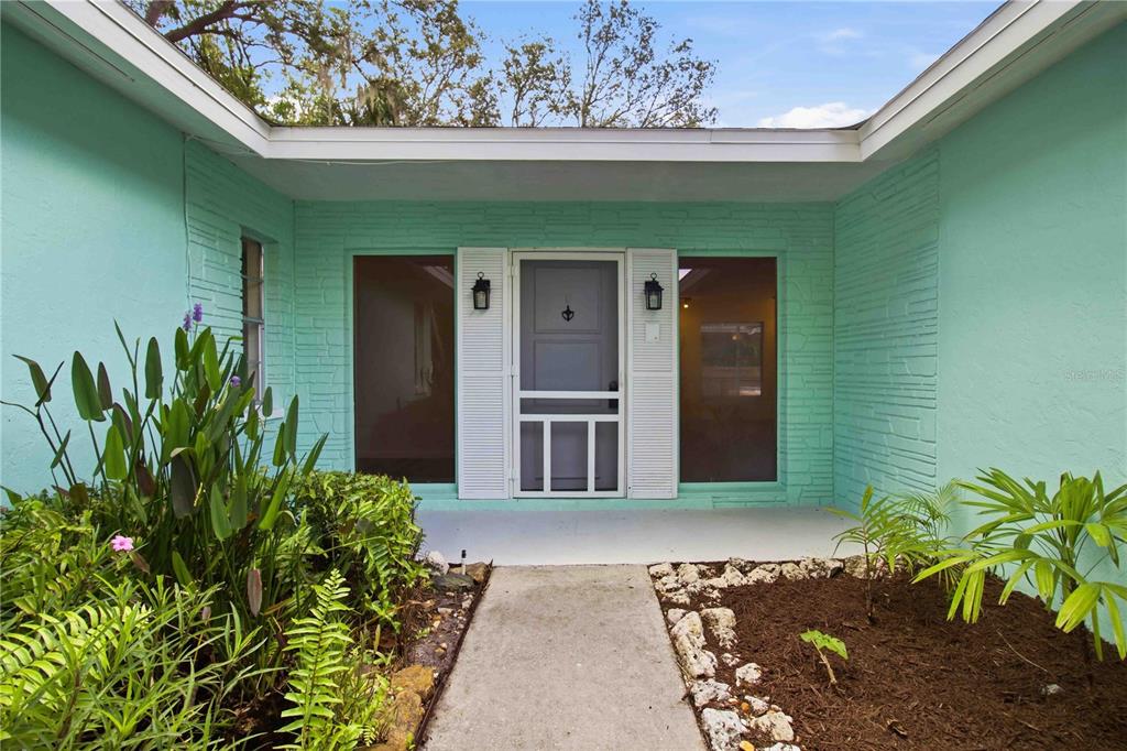 The exterior view shows a mint green house with a central screened door and walkway — 3629 EGERTON CIRCLE, SARASOTA, FL
