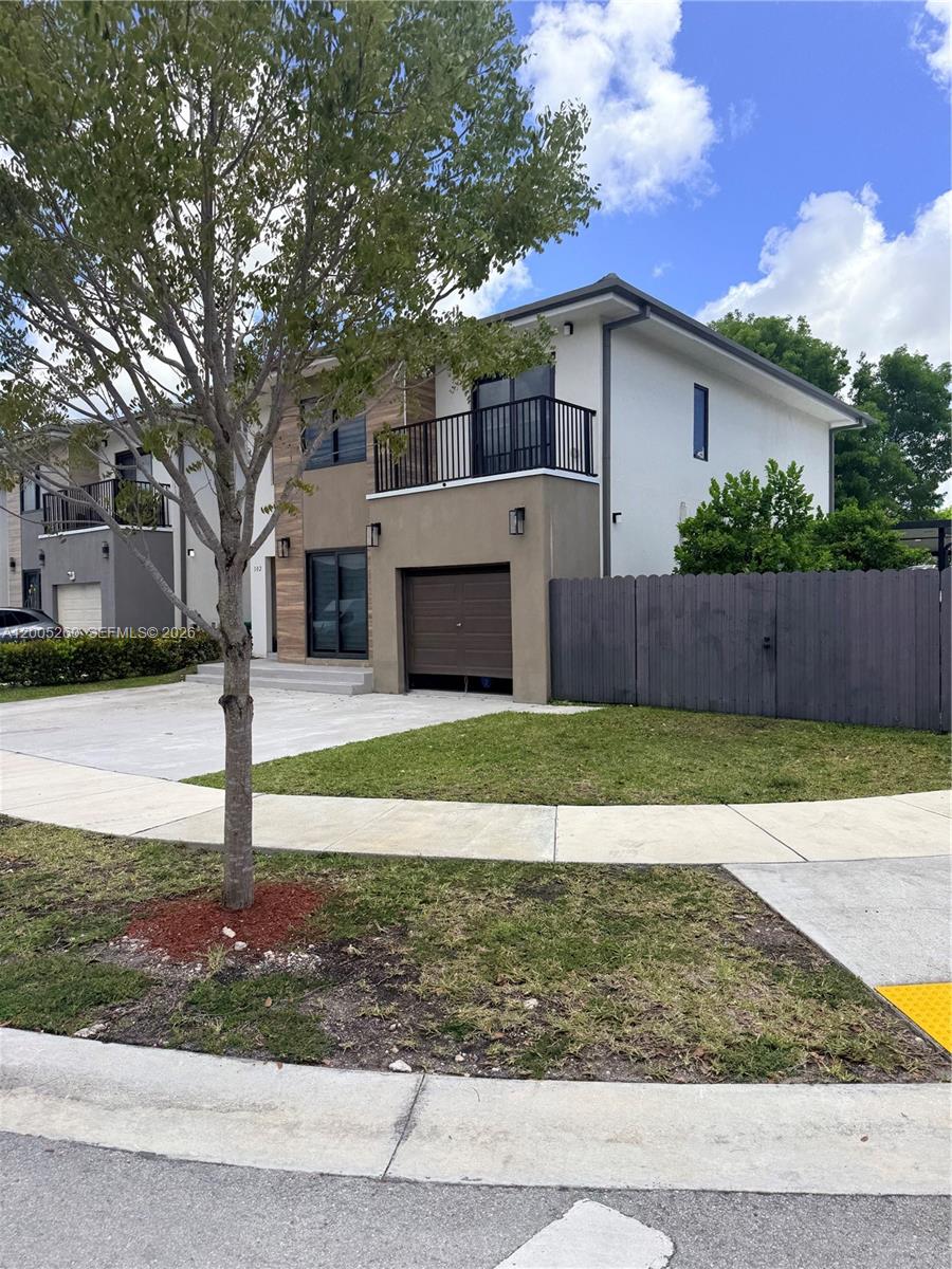 A two-story modern house with a garage, balcony, and a wooden fence — 102 NW 10th Pl, Florida City FL 33034, FLORIDA CITY, FL