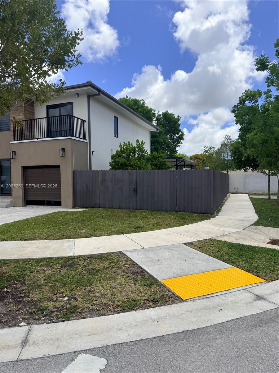 A two-story house with a garage and a balcony sits behind a dark wooden fence — 102 NW 10th Pl, Florida City FL 33034, FLORIDA CITY, FL