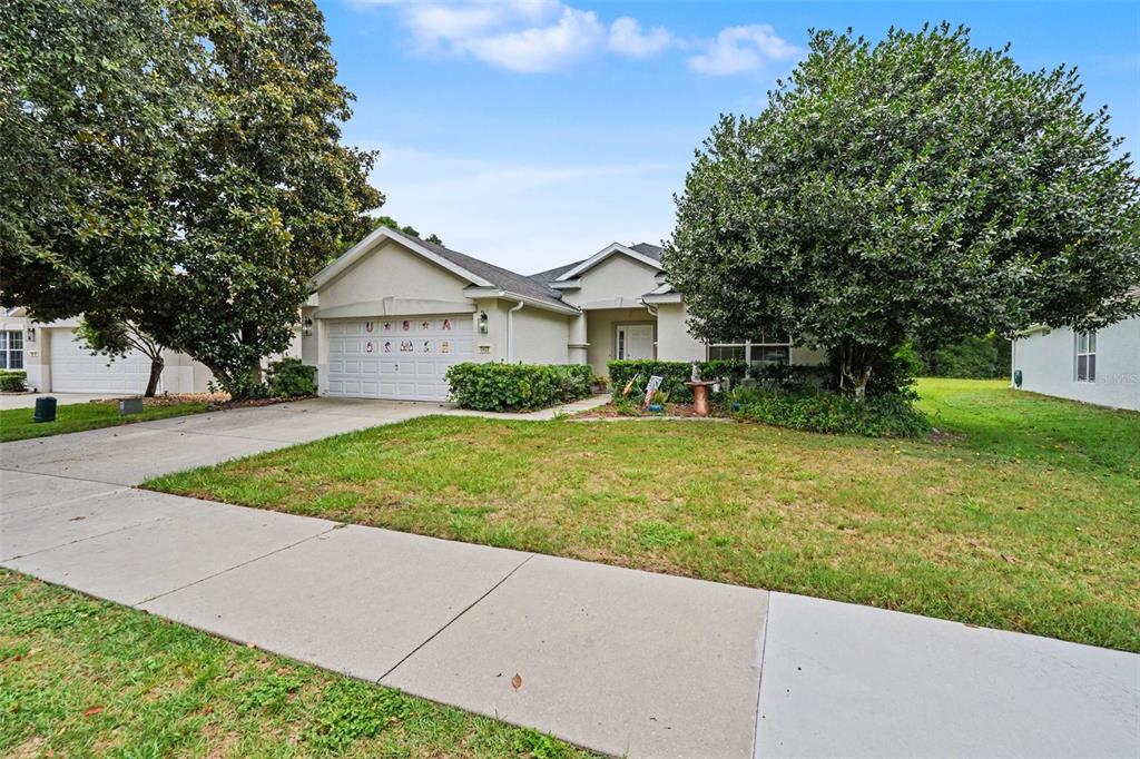 A single-story suburban house with a two-car garage, a concrete driveway, and mature trees — 5520 SW 45TH STREET, OCALA, FL