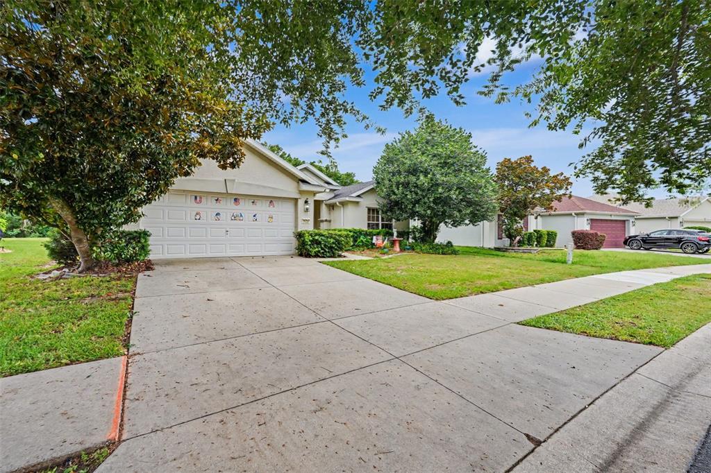 A single-story house with a two-car garage, concrete driveway, and mature trees in front — 5520 SW 45TH STREET, OCALA, FL