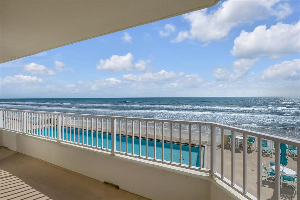 A balcony overlooks a swimming pool and the ocean under a partly cloudy sky — 2937 S ATLANTIC AVENUE UNIT 206, DAYTONA BEACH SHORES, FL