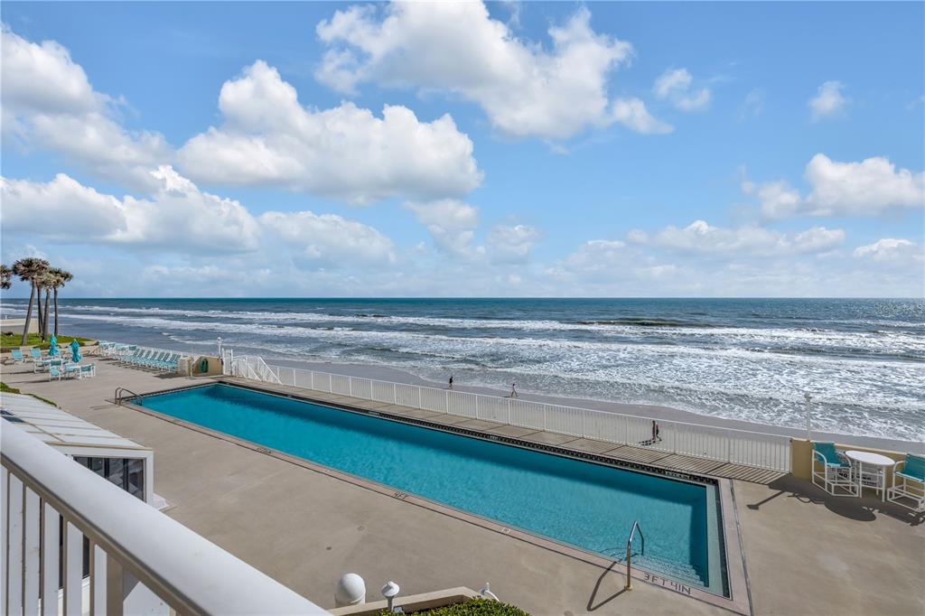 An elevated view of a rectangular swimming pool located on a patio beside the ocean — 2937 S ATLANTIC AVENUE UNIT 206, DAYTONA BEACH SHORES, FL