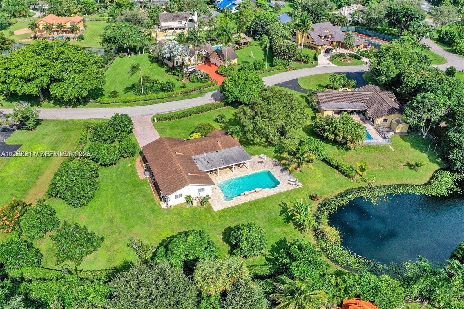 An aerial view shows a house with a pool and pond in a residential neighborhood — 11030 SW 42nd Ct, Davie FL 33328, DAVIE, FL