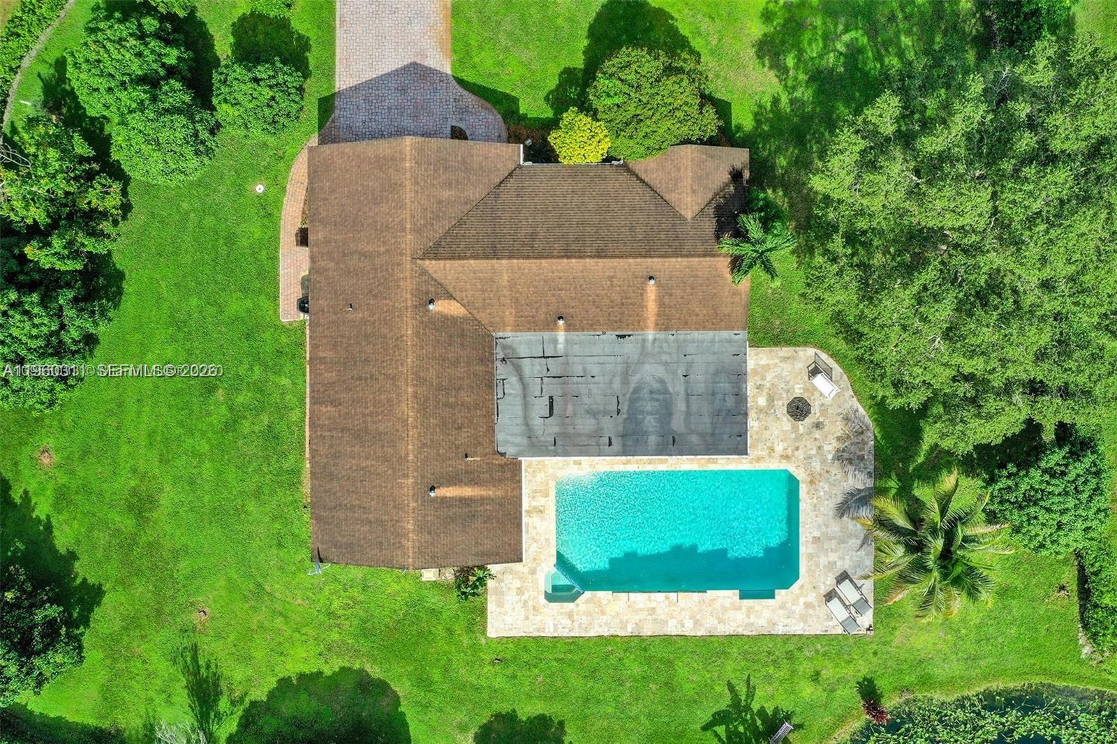 An aerial view shows a house with a brown roof, a pool, and surrounding lawn — 11030 SW 42nd Ct, Davie FL 33328, DAVIE, FL