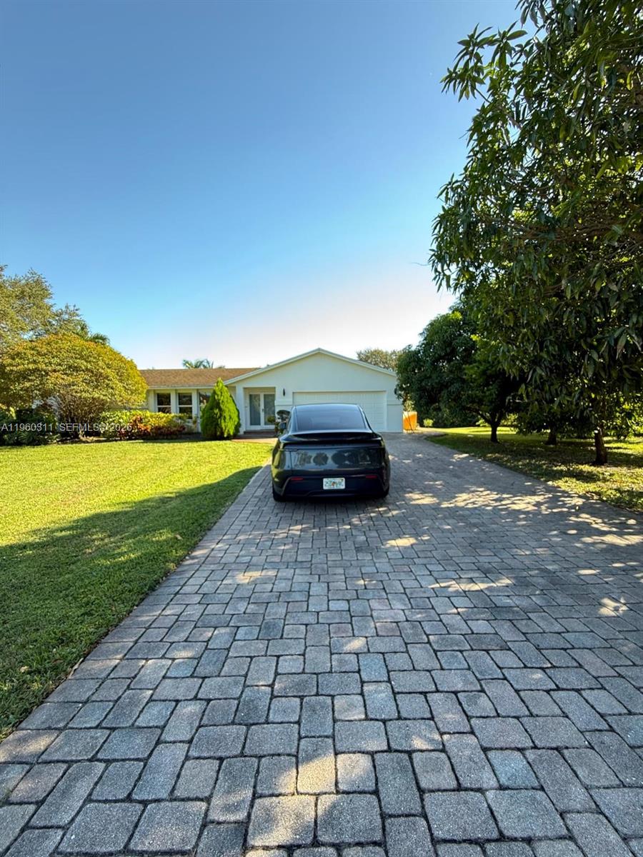 A dark sedan is parked on a paved driveway in front of a single-story house — 11030 SW 42nd Ct, Davie FL 33328, DAVIE, FL