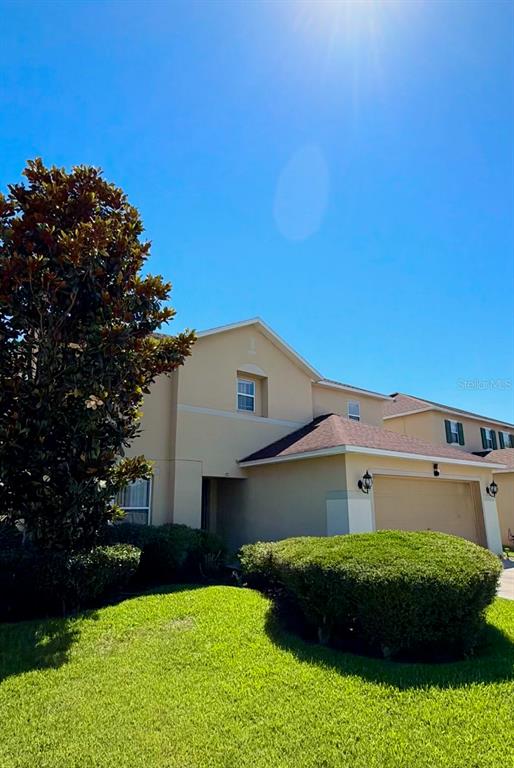 A two-story suburban house with a tan exterior, a two-car garage, and manicured landscaping — 32111 BROOKSTONE DRIVE, WESLEY CHAPEL, FL