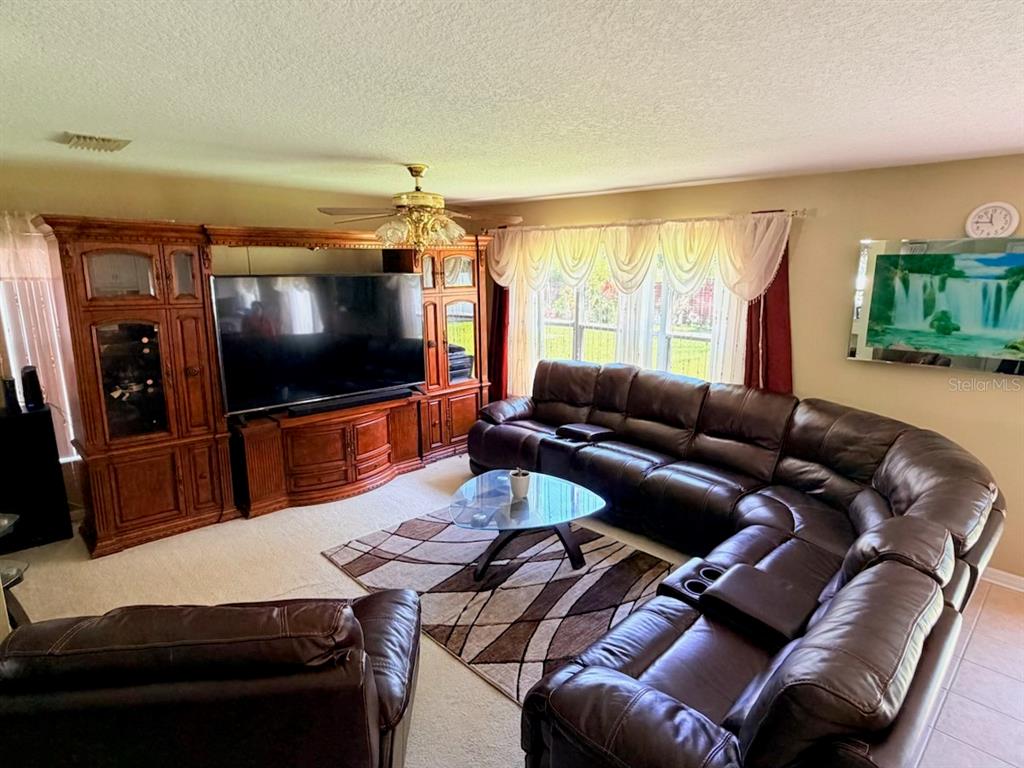A living room features a large brown sectional sofa, a wooden entertainment center, and a rug — 32111 BROOKSTONE DRIVE, WESLEY CHAPEL, FL
