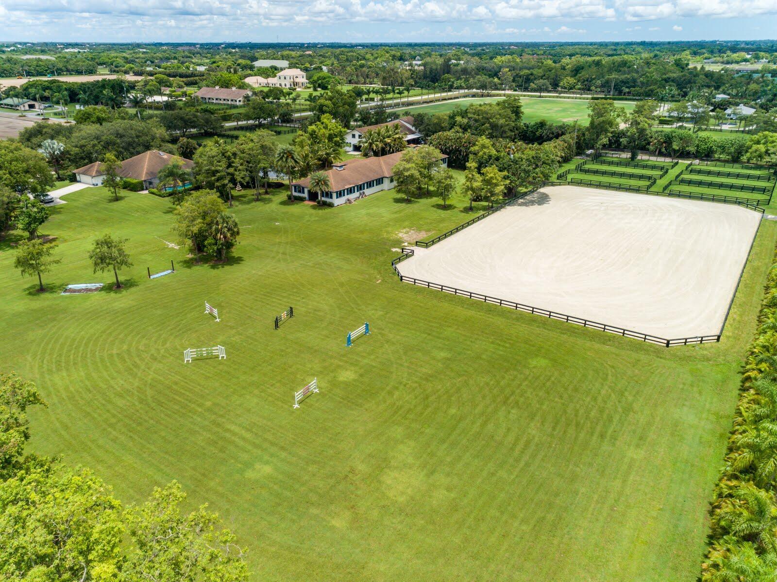 An aerial view of a property featuring a large riding arena, jumps, and residential buildings — 5656 South Shore Boulevard, Wellington FL 33449, WELLINGTON, FL