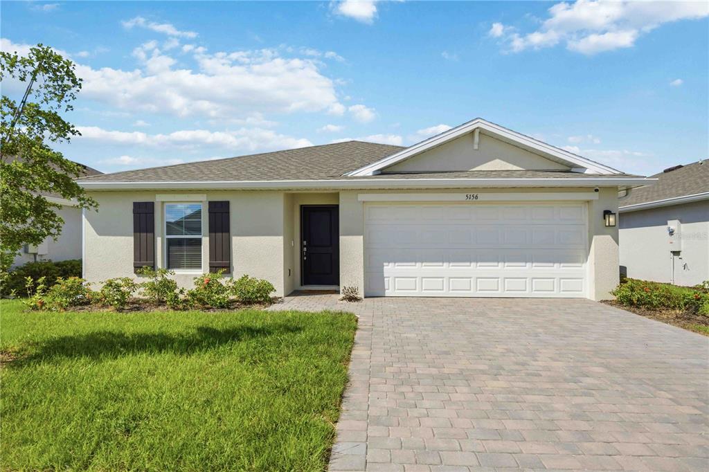 A single-story house with a beige stucco exterior, a two-car garage, and a paver driveway — 5156 SCHUBERT TRAIL, NORTH PORT, FL