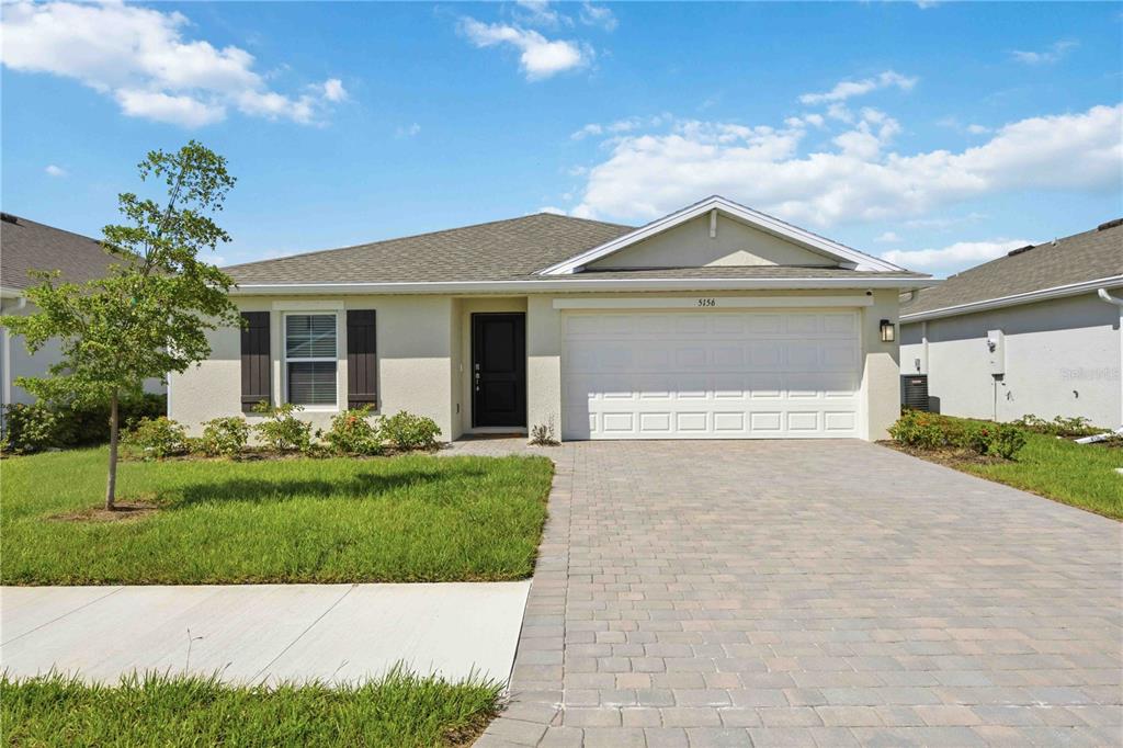 A single-story suburban house with a paved driveway, two-car garage, and a small front lawn — 5156 SCHUBERT TRAIL, NORTH PORT, FL