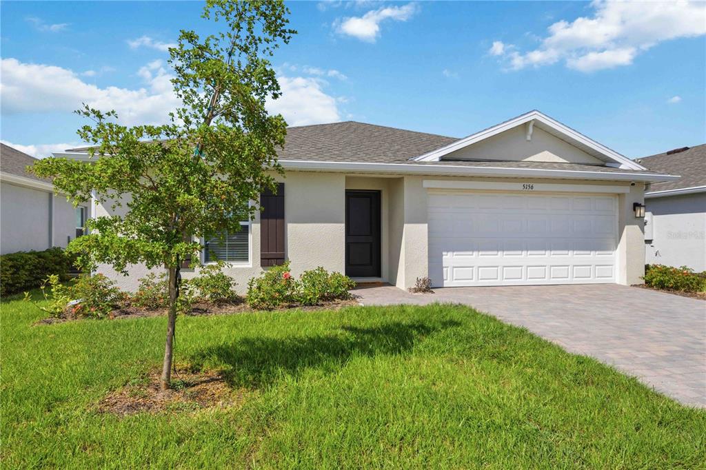 A single-story house with a beige stucco exterior, a two-car garage, and a front lawn — 5156 SCHUBERT TRAIL, NORTH PORT, FL