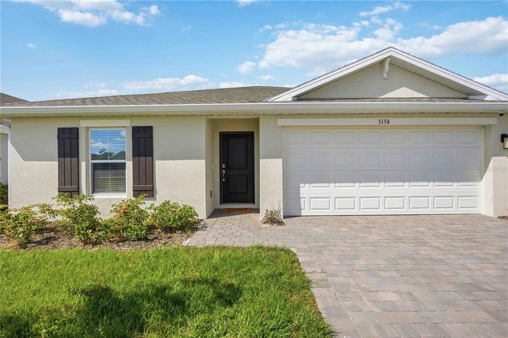 A single-story house with a beige stucco exterior, dark shutters, and a paved driveway — 5156 SCHUBERT TRAIL, NORTH PORT, FL
