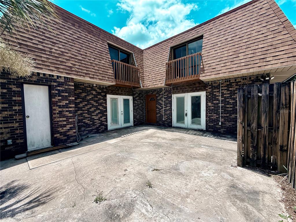 A brick building exterior features a concrete courtyard, two balconies, and multiple entry doors — 202 TERRACE COURT, SANFORD, FL